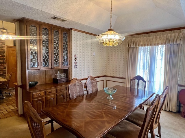 dining room featuring a textured ceiling, lofted ceiling, light carpet, visible vents, and wallpapered walls