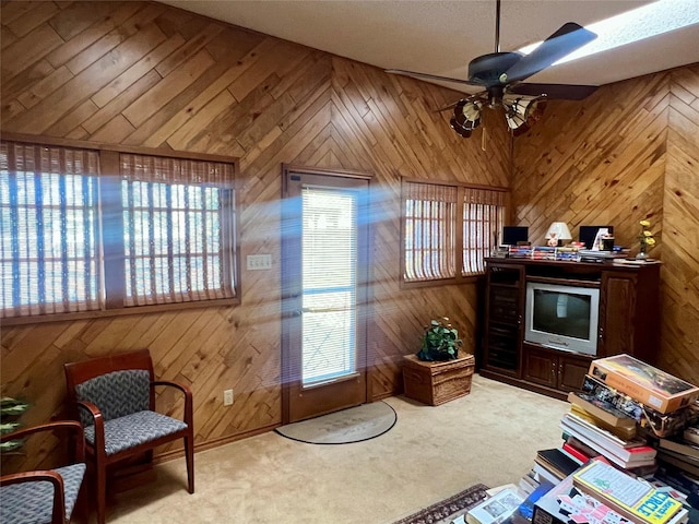 sitting room with a ceiling fan, carpet, and wooden walls