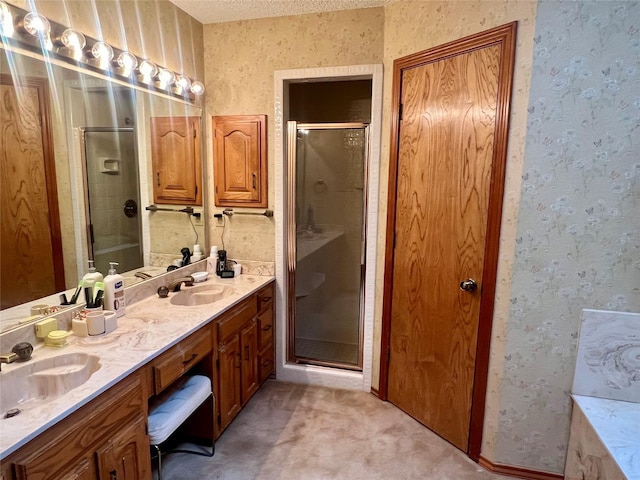 bathroom featuring a sink, a shower stall, and wallpapered walls