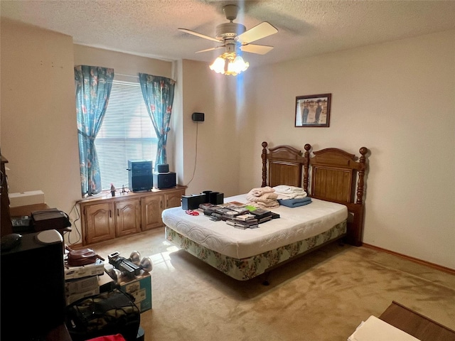 bedroom with baseboards, a ceiling fan, a textured ceiling, and light colored carpet