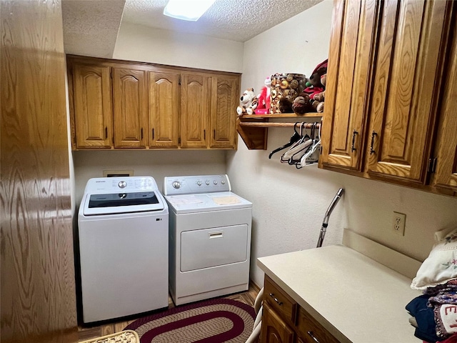 laundry area featuring washing machine and dryer, cabinet space, and a textured ceiling