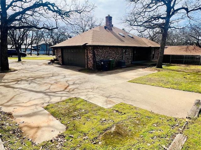 view of property exterior featuring a garage, brick siding, concrete driveway, a yard, and a chimney