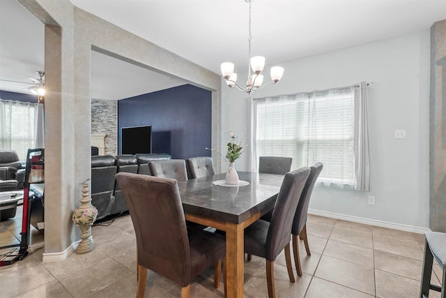 dining area with ceiling fan with notable chandelier, baseboards, and light tile patterned flooring