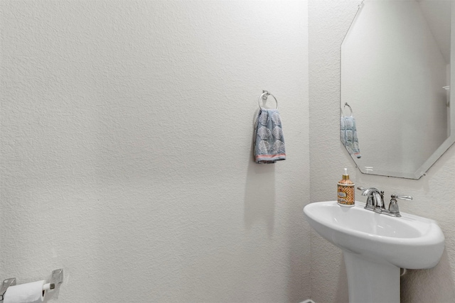 bathroom with a textured wall and a sink