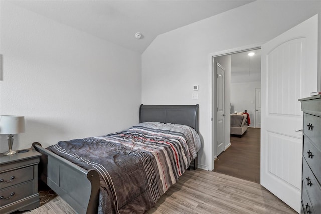 bedroom with light wood-type flooring and vaulted ceiling