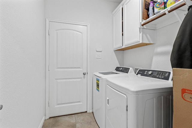 laundry room featuring washing machine and dryer, cabinet space, and baseboards