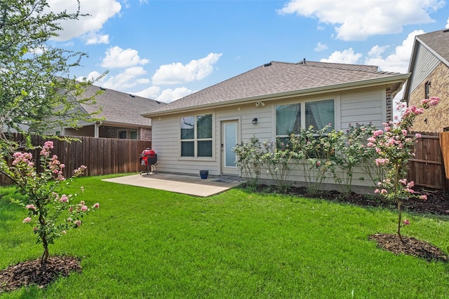 back of house with a patio area, a lawn, a fenced backyard, and roof with shingles