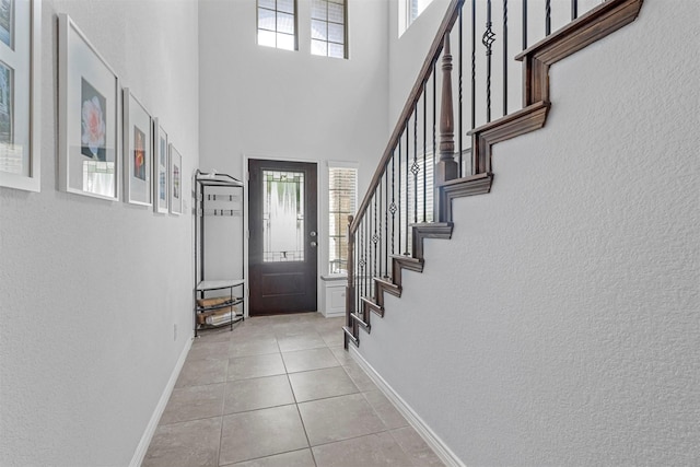 entryway with light tile patterned floors, plenty of natural light, and baseboards