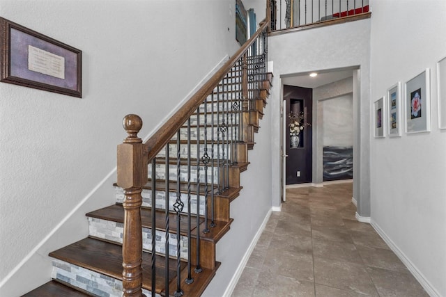 staircase featuring a high ceiling and baseboards