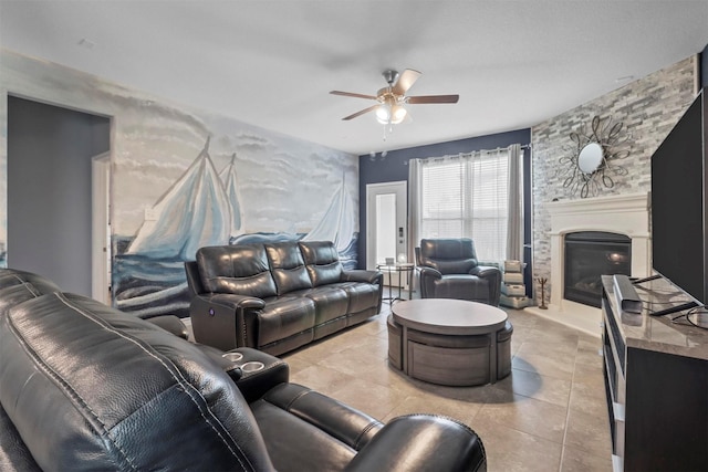 living area with a large fireplace, light tile patterned floors, and a ceiling fan