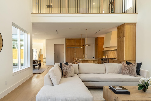 living room with light wood-style floors, a towering ceiling, and baseboards