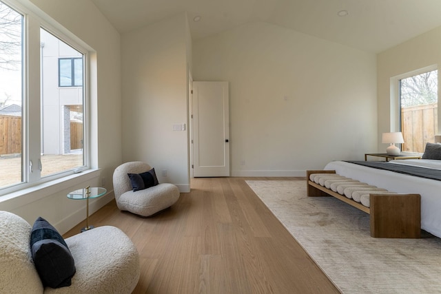 bedroom with lofted ceiling, light wood-type flooring, and baseboards