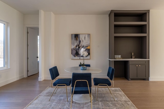 dining room with built in shelves, baseboards, and wood finished floors