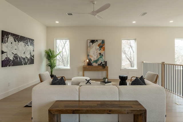 living area with visible vents, a wealth of natural light, and wood finished floors