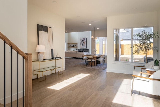living area with baseboards, wood finished floors, and stairs