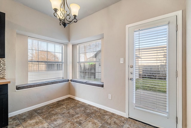 entryway featuring a chandelier and baseboards