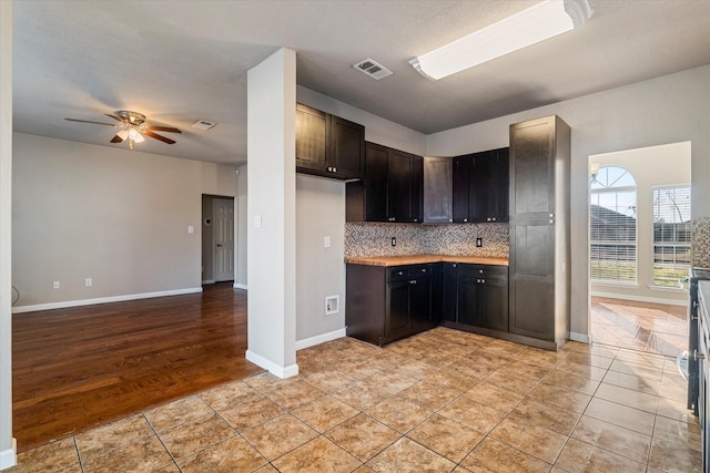 kitchen featuring light tile patterned floors, baseboards, visible vents, decorative backsplash, and a ceiling fan