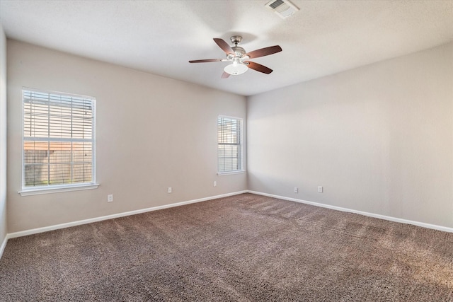 carpeted spare room with baseboards, visible vents, and a ceiling fan