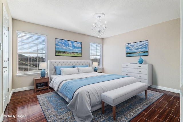 bedroom with baseboards, wood finish floors, and an inviting chandelier