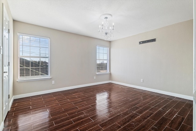 spare room with baseboards, a notable chandelier, and wood finished floors