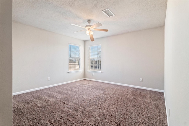 empty room with carpet, visible vents, ceiling fan, a textured ceiling, and baseboards