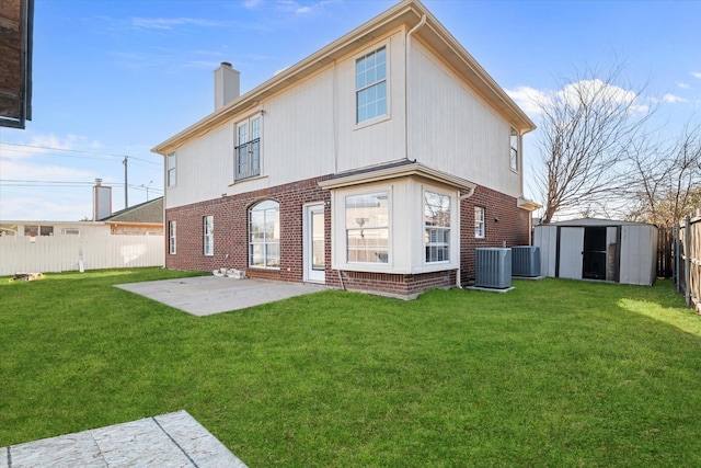 back of property with an outbuilding, brick siding, a chimney, a storage unit, and a fenced backyard