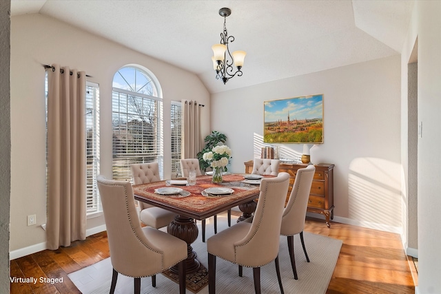 dining room with lofted ceiling, light wood-style floors, baseboards, and a notable chandelier