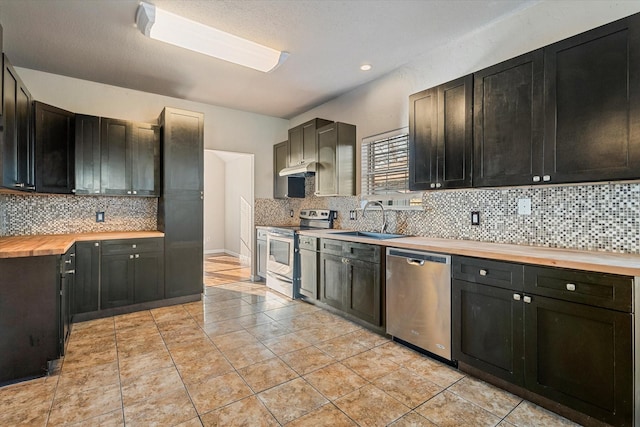 kitchen with light tile patterned floors, wood counters, stainless steel appliances, dark cabinetry, and a sink