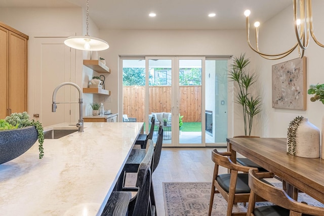 interior space with a breakfast bar, decorative light fixtures, light wood-style floors, a sink, and recessed lighting