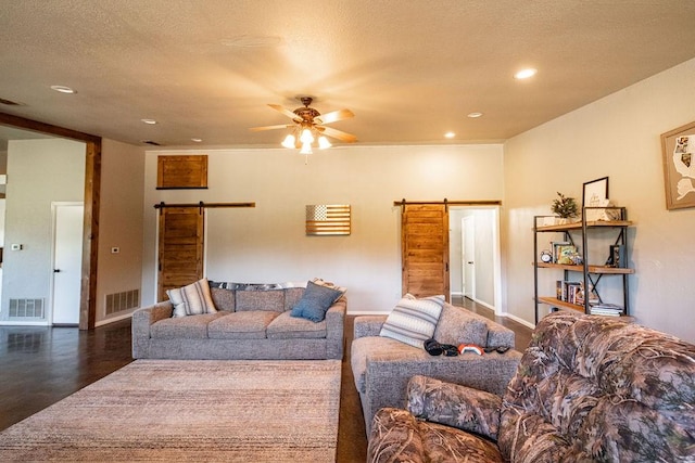 living room with a ceiling fan, visible vents, and a barn door