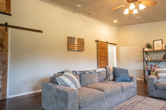 living area with a barn door, baseboards, ceiling fan, and wood finished floors