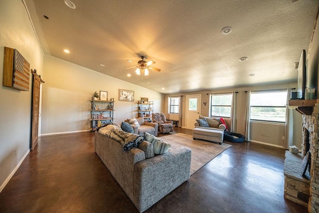 living area with lofted ceiling, concrete floors, a textured ceiling, and a stone fireplace