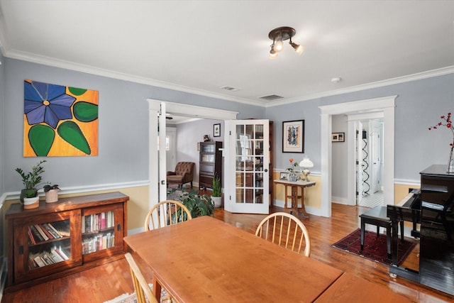 dining space with ornamental molding, french doors, visible vents, and wood finished floors