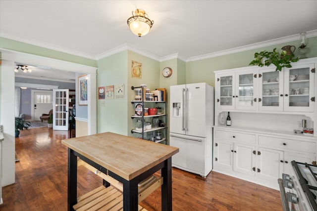 kitchen with white refrigerator with ice dispenser, white cabinetry, dark wood-style floors, glass insert cabinets, and crown molding