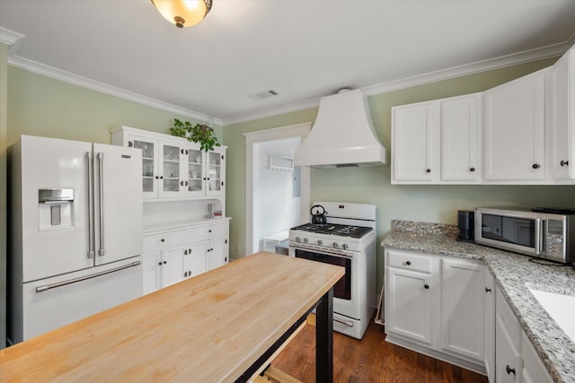 kitchen with crown molding, white appliances, visible vents, and custom range hood