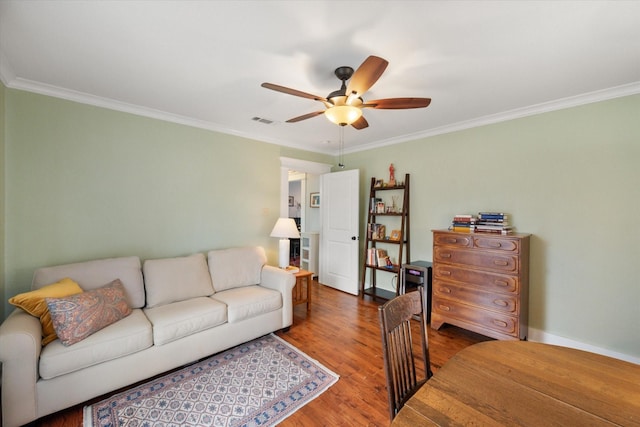 living room featuring ornamental molding, a ceiling fan, visible vents, and wood finished floors