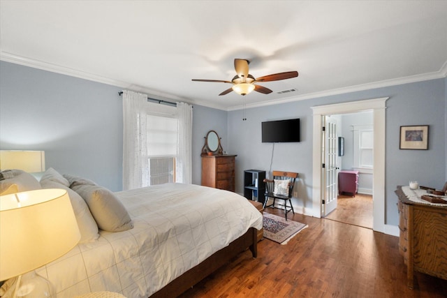 bedroom featuring a ceiling fan, visible vents, wood finished floors, and ornamental molding