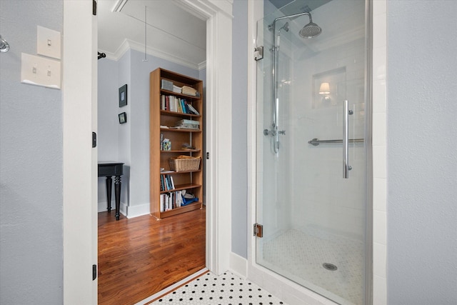 bathroom featuring a stall shower, baseboards, wood finished floors, crown molding, and built in shelves