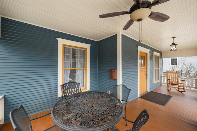 wooden deck with a ceiling fan, outdoor dining area, and covered porch