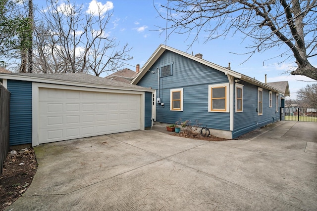 view of side of home featuring a garage, fence, and an outbuilding