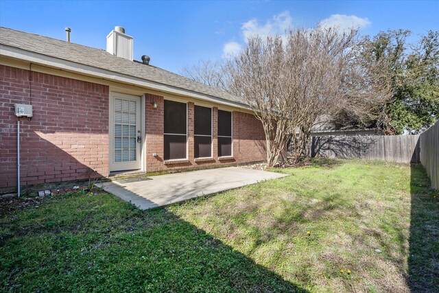 back of property with a patio, a fenced backyard, a chimney, a yard, and brick siding