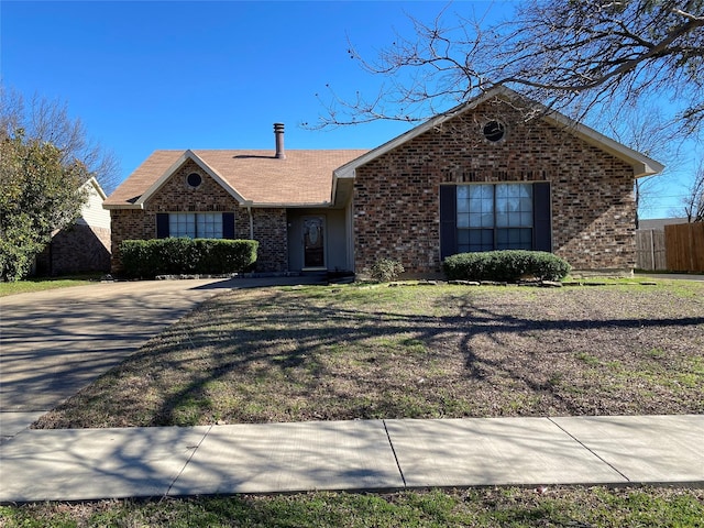 ranch-style home with brick siding, a front lawn, and fence