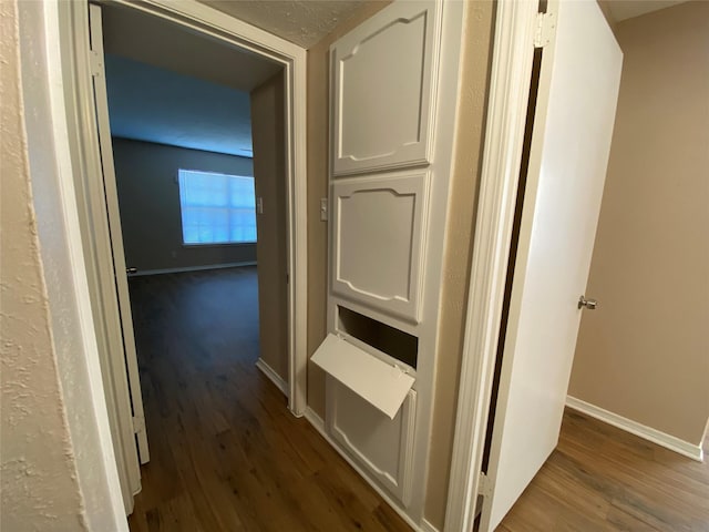hall with dark wood-type flooring and baseboards