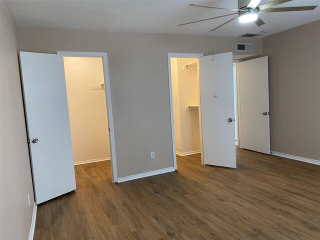 unfurnished bedroom with wood finished floors, visible vents, baseboards, a closet, and a walk in closet