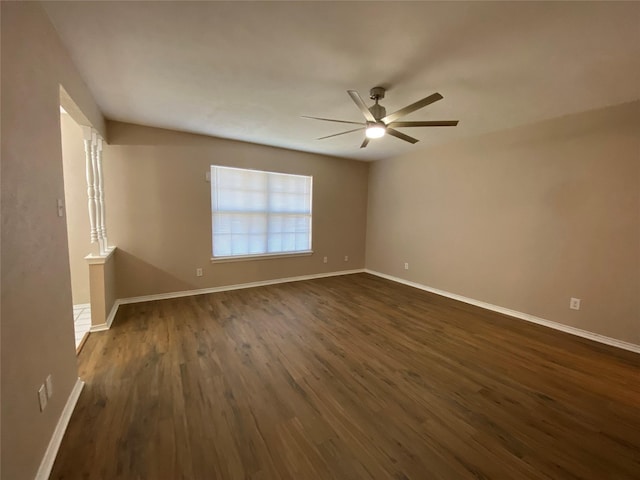 spare room featuring dark wood-style floors, baseboards, and ceiling fan