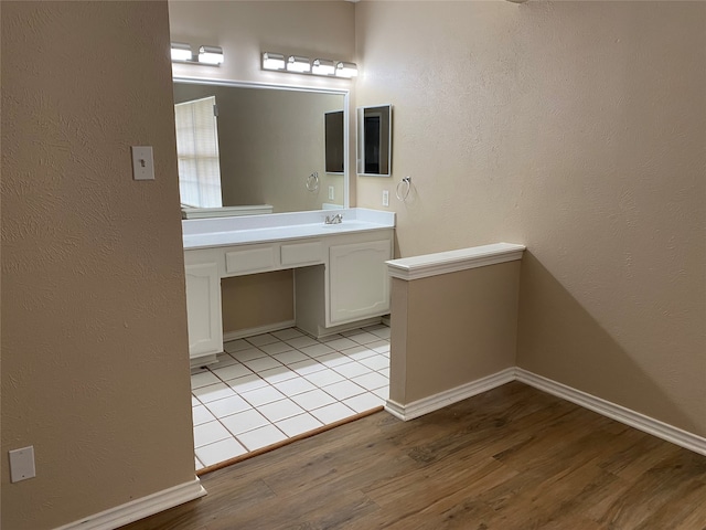 bathroom featuring vanity, wood finished floors, baseboards, and a textured wall