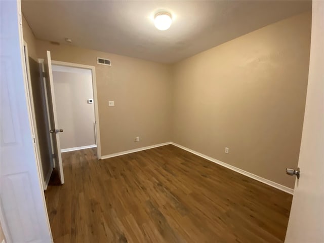 unfurnished room with visible vents, baseboards, and dark wood-type flooring