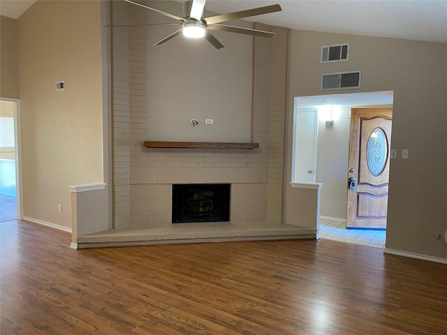 unfurnished living room with a fireplace, wood finished floors, visible vents, and a ceiling fan