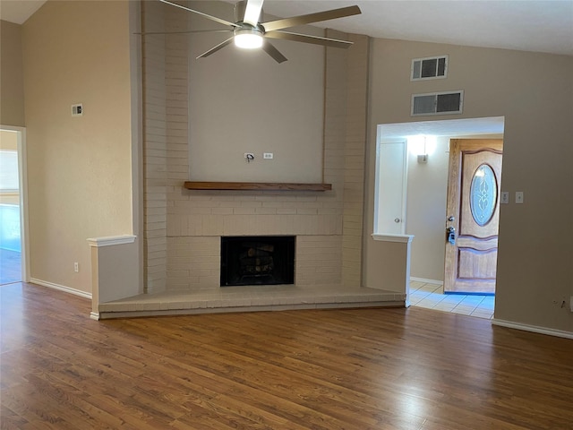 unfurnished living room featuring a fireplace, wood finished floors, visible vents, and ceiling fan