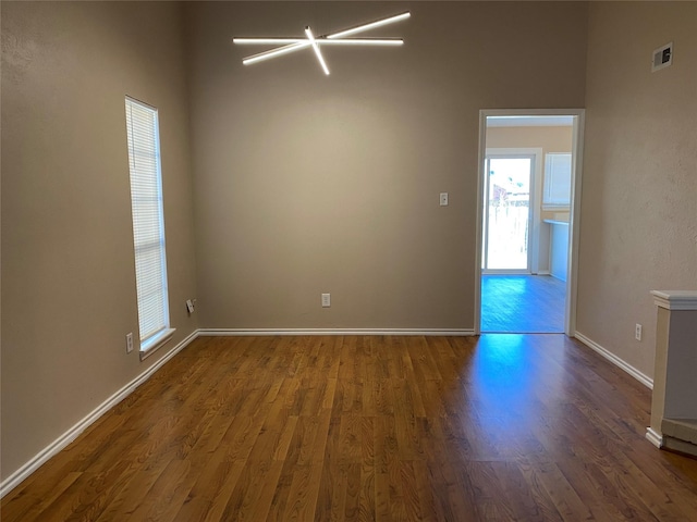 spare room with visible vents, baseboards, and wood finished floors